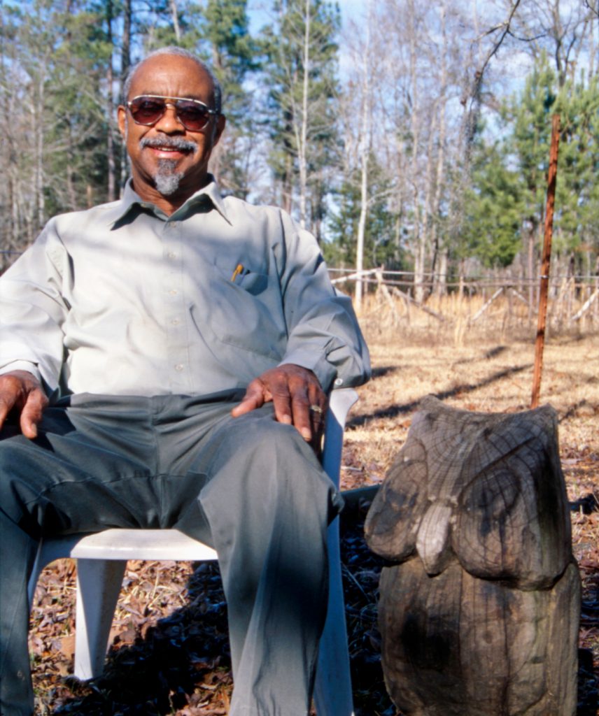 George Berry with a large version of his signature owl carving.
