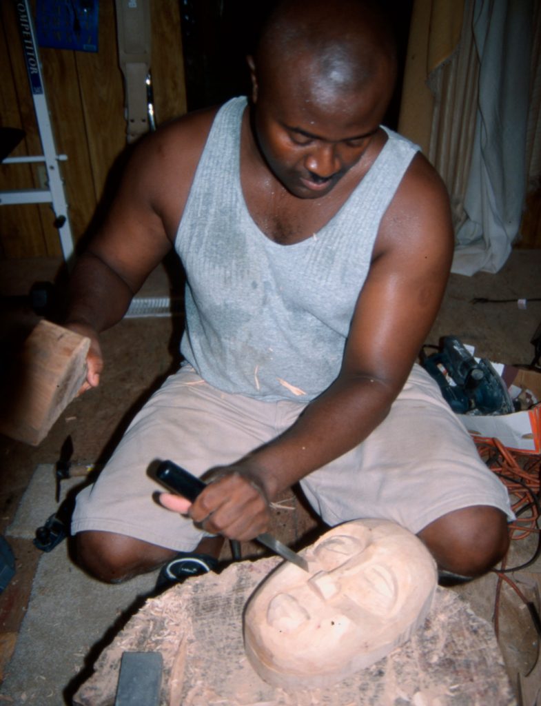 Amoah carving a mask in his workshop.