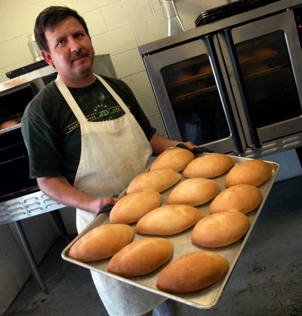 Jose Flores from Panaderia Nuevo Leon in Vardaman removes a tray of bolillos (white bread) from the baking oven (photo by Kate Medley for the Mississippi Arts Commission).